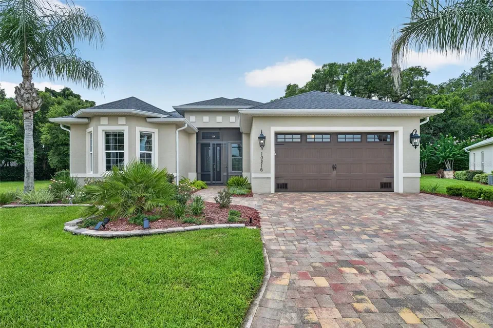 10216 Julia Isles Ave, Oxford, with palms, a paver driveway and a two-car garage